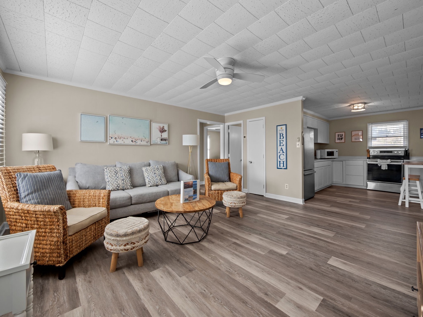 Step into your bright, open living space where coastal charm meets modern comfort with stylish wicker seating and a fully equipped kitchen.