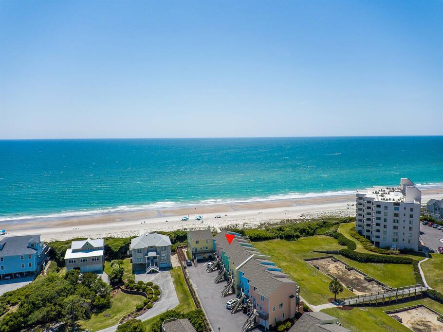 Aerial view of beachfront vacation properties along pristine coastline with white sand and turquoise waters.