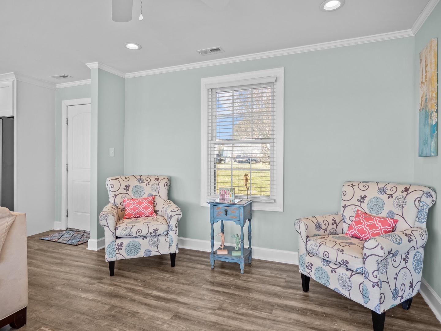 Sink into these charming floral chairs by the window, where soft mint walls and warm light create your perfect reading retreat.