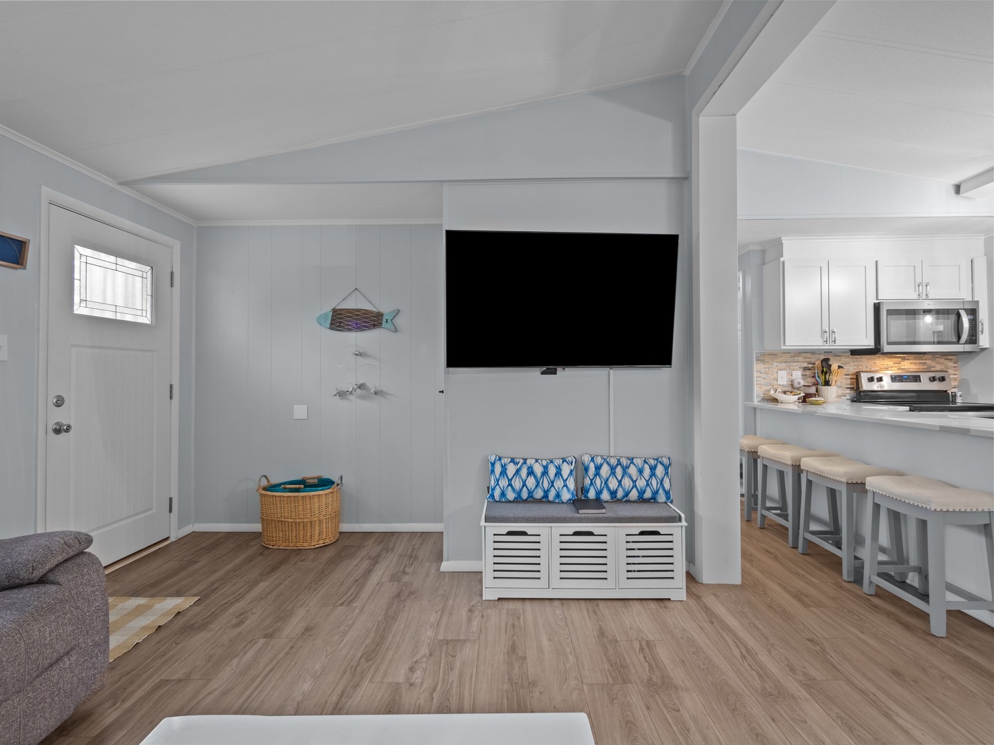 Relax in this bright, coastal-themed living space where you'll find a wall-mounted TV, comfortable seating, and an open kitchen perfect for vacation cooking.