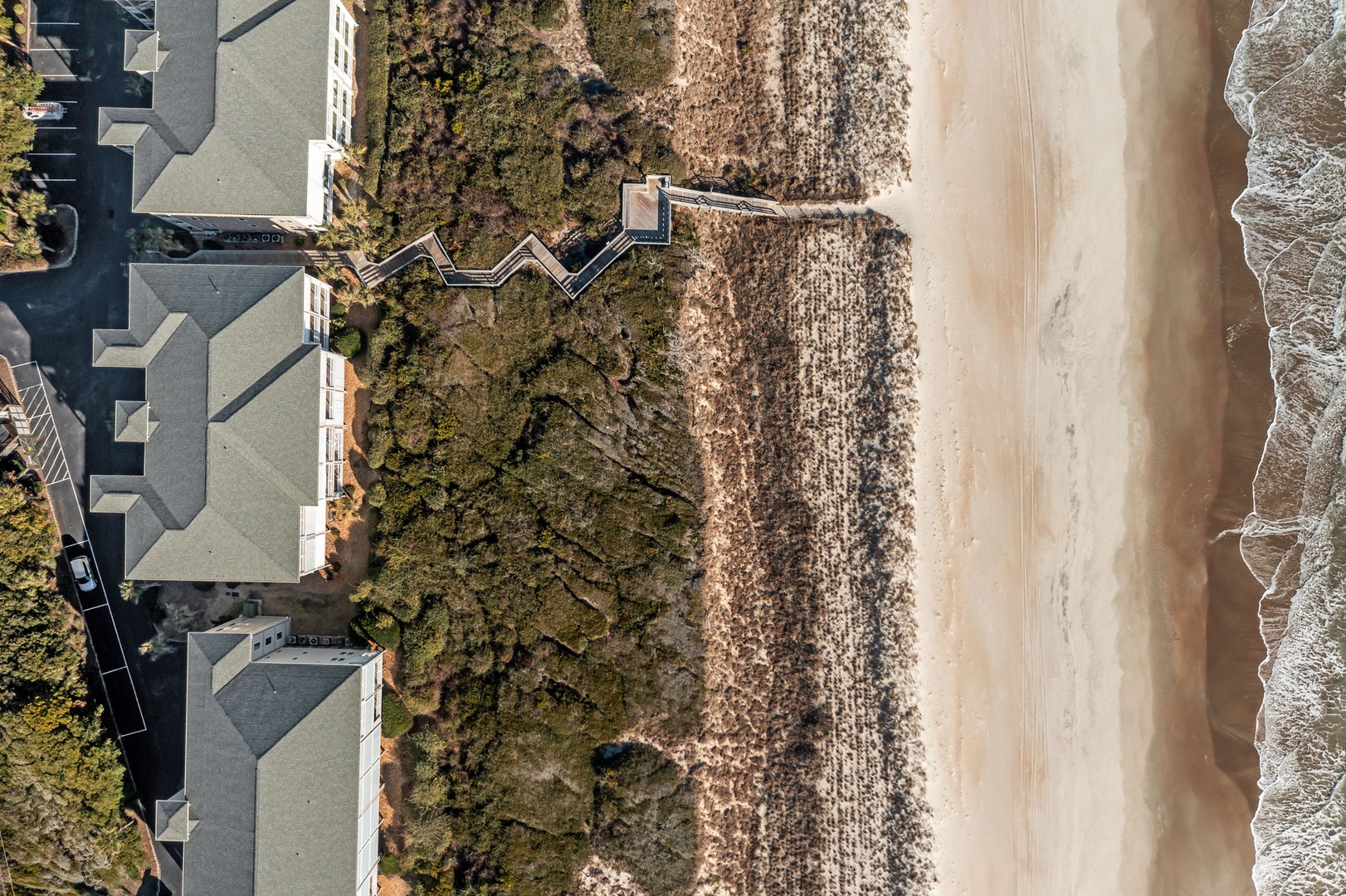 Aerial view showcasing the property's prime beachfront location with direct sandy beach access and oceanfront positioning.