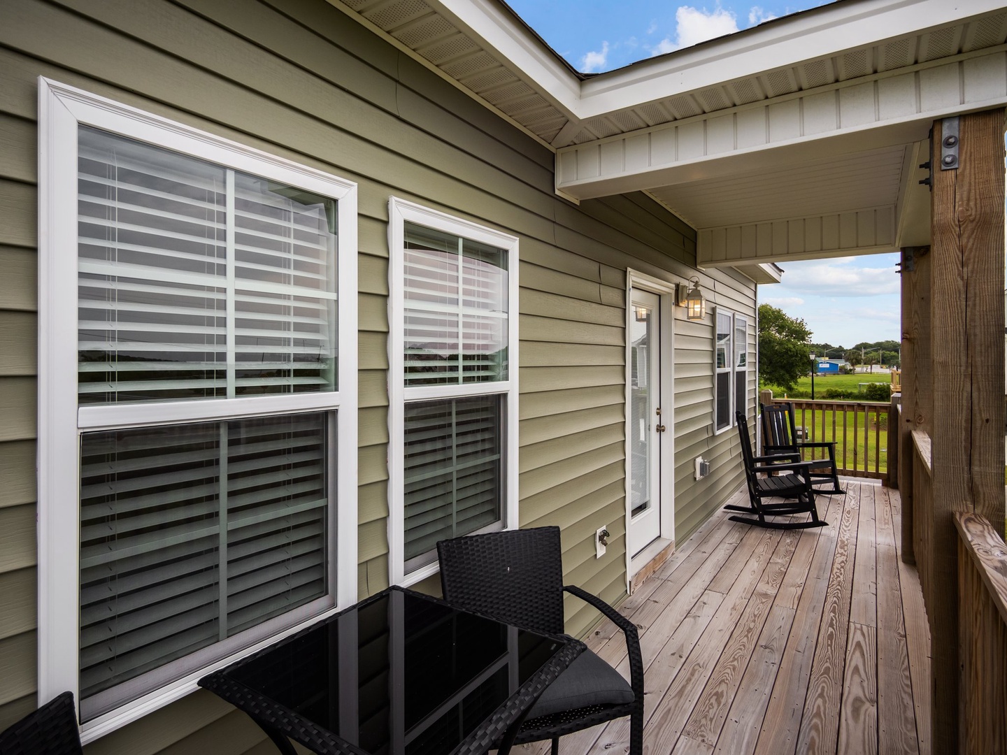 Your covered deck stretches along the property with rocking chairs and outdoor seating, perfect for morning coffee or evening relaxation.