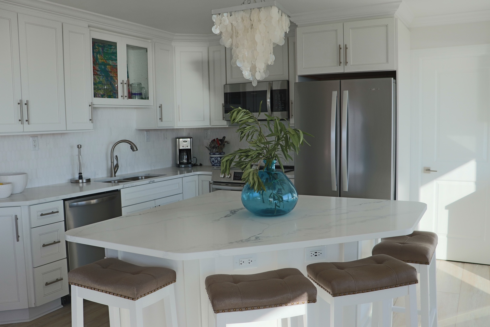Your bright, modern kitchen welcomes you with gleaming white cabinets, marble countertops, and stylish seating for casual meals or morning coffee.