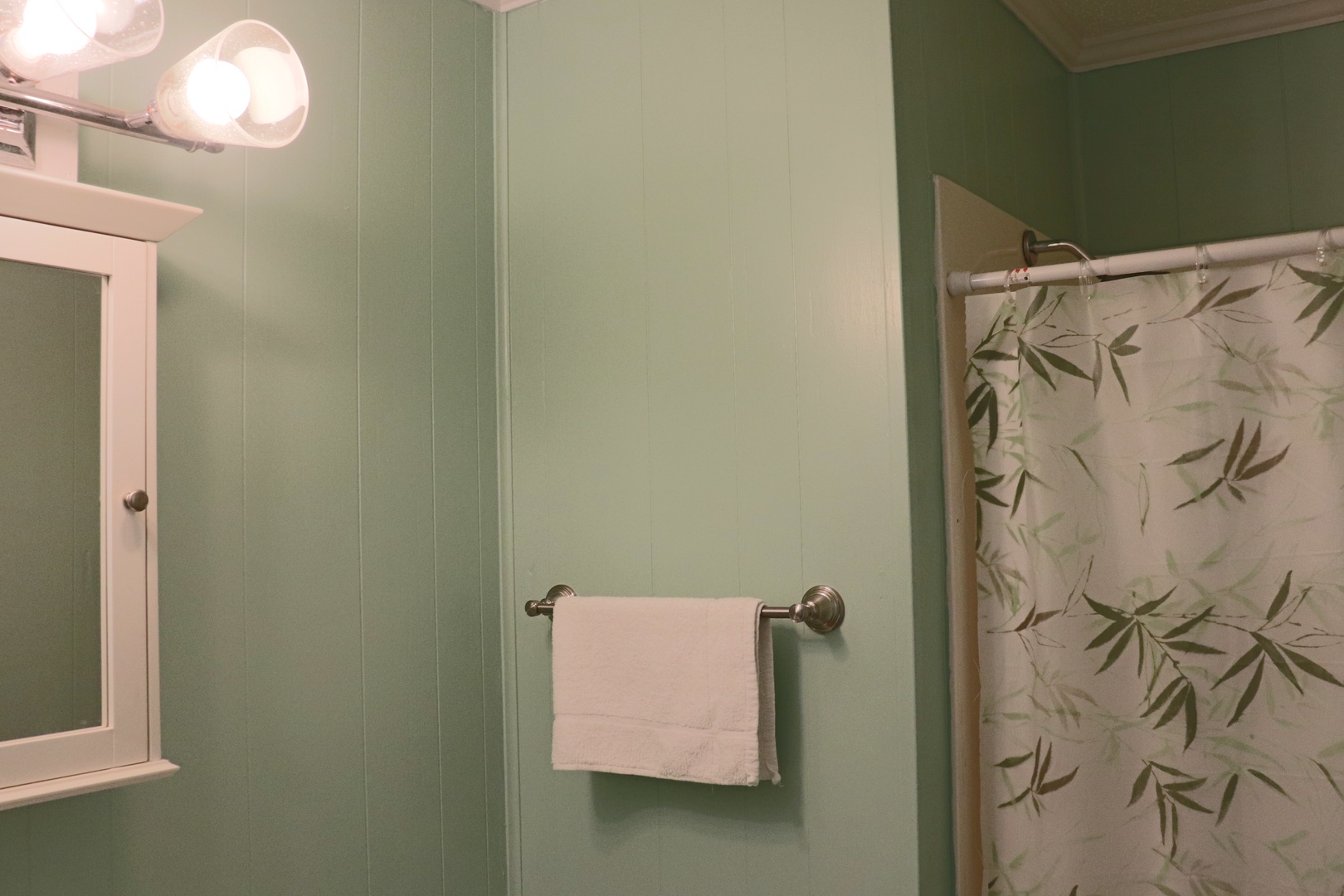 Your private bathroom features soothing sage green walls and a botanical shower curtain that creates a serene, spa-like retreat.