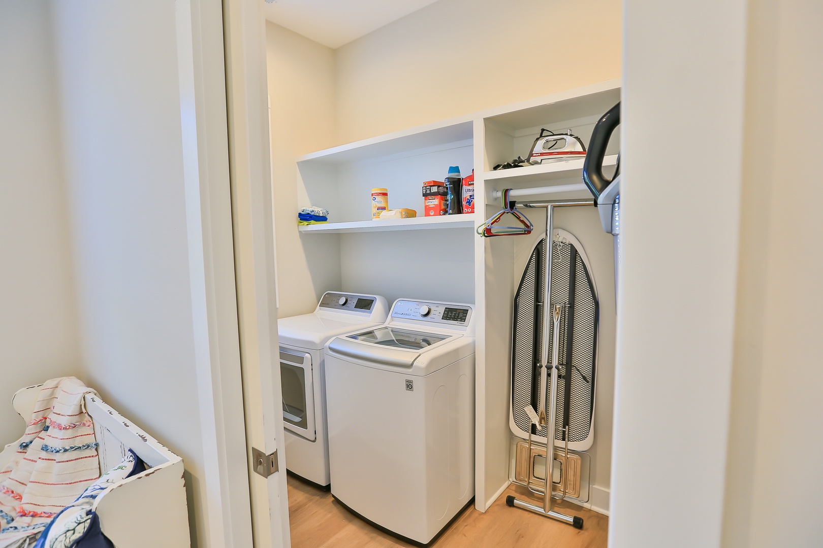 Your laundry room features modern washer and dryer with built-in shelving for supplies and an ironing board for effortless garment care.