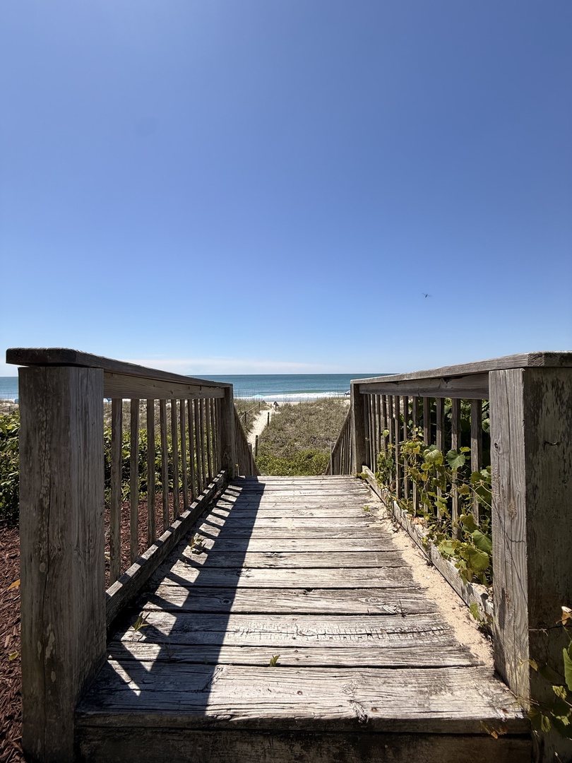 Weathered wooden dock stretches over calm waters, framed by lush greenery—a serene spot for quiet reflection or a refreshing dip.