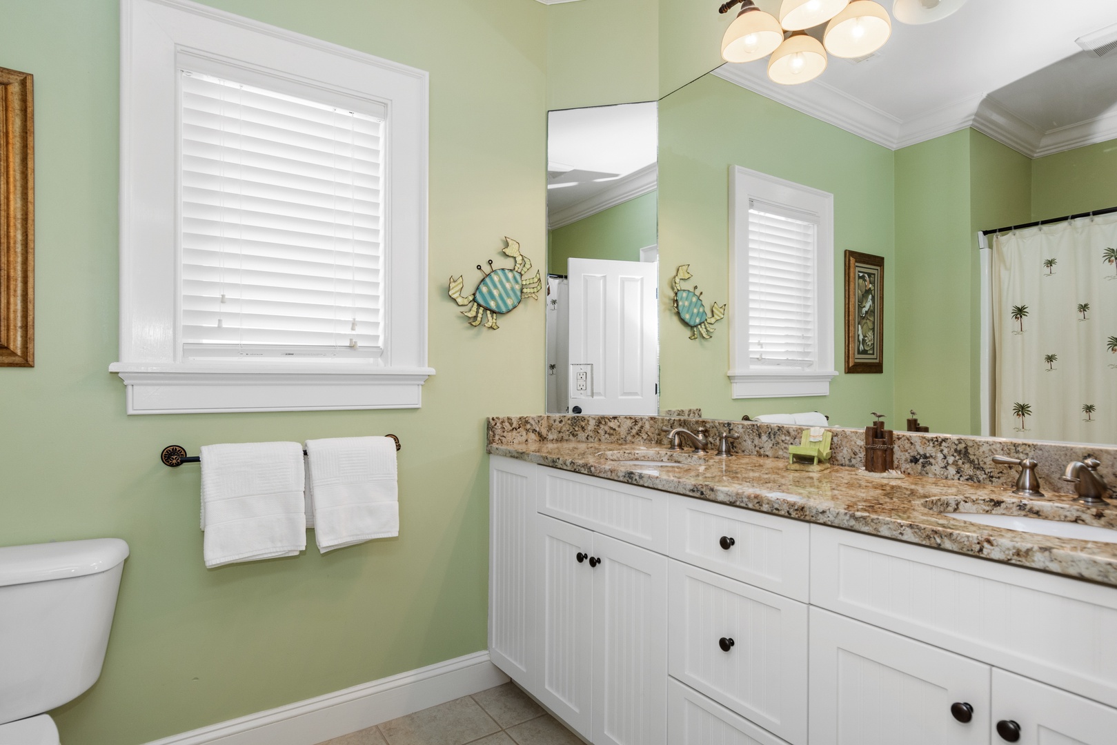 Unwind in your bright, coastal-themed bathroom featuring double vanities, granite countertops, and charming crab wall art.