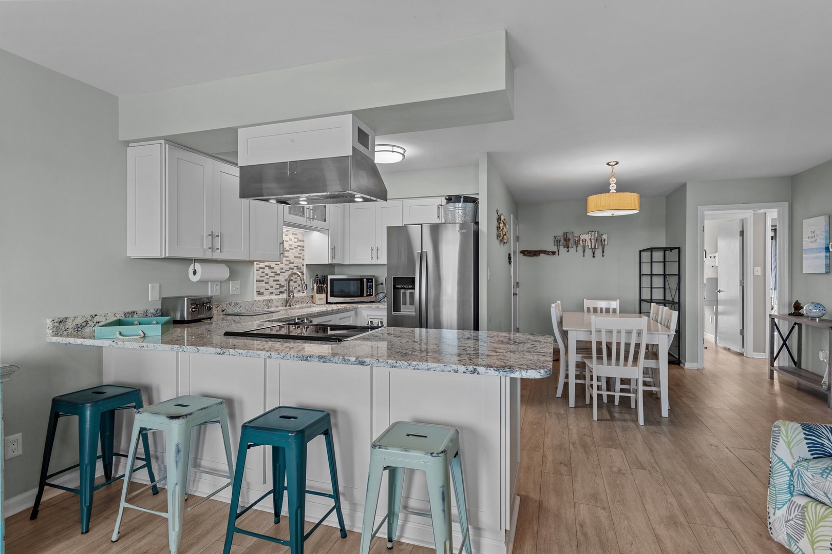 Your modern kitchen features granite countertops, stainless steel appliances, and colorful bar seating perfect for morning coffee or casual meals together.