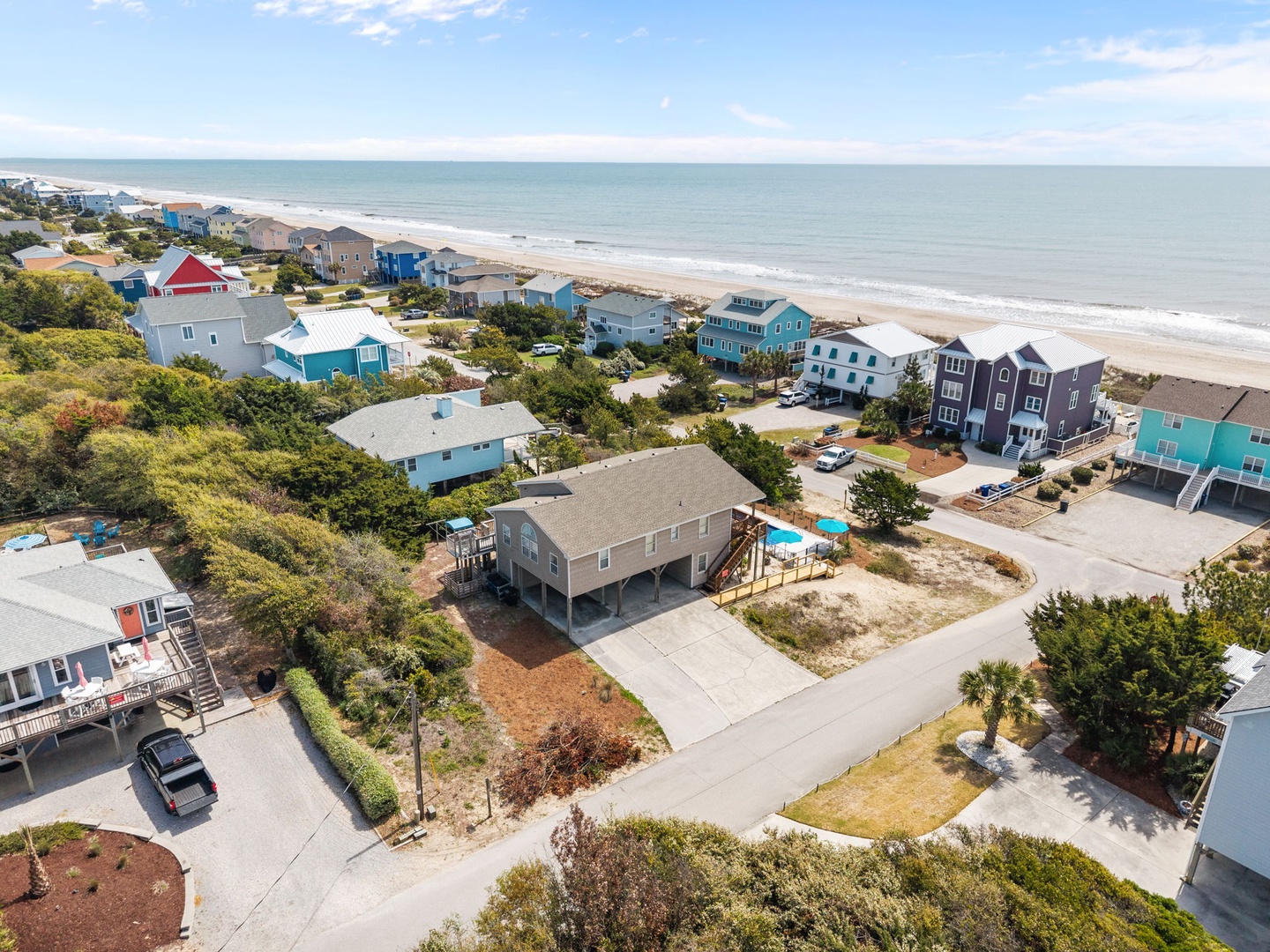 Beachfront vacation rental community with colorful coastal homes, swimming pool, and direct beach access on pristine sandy shoreline.