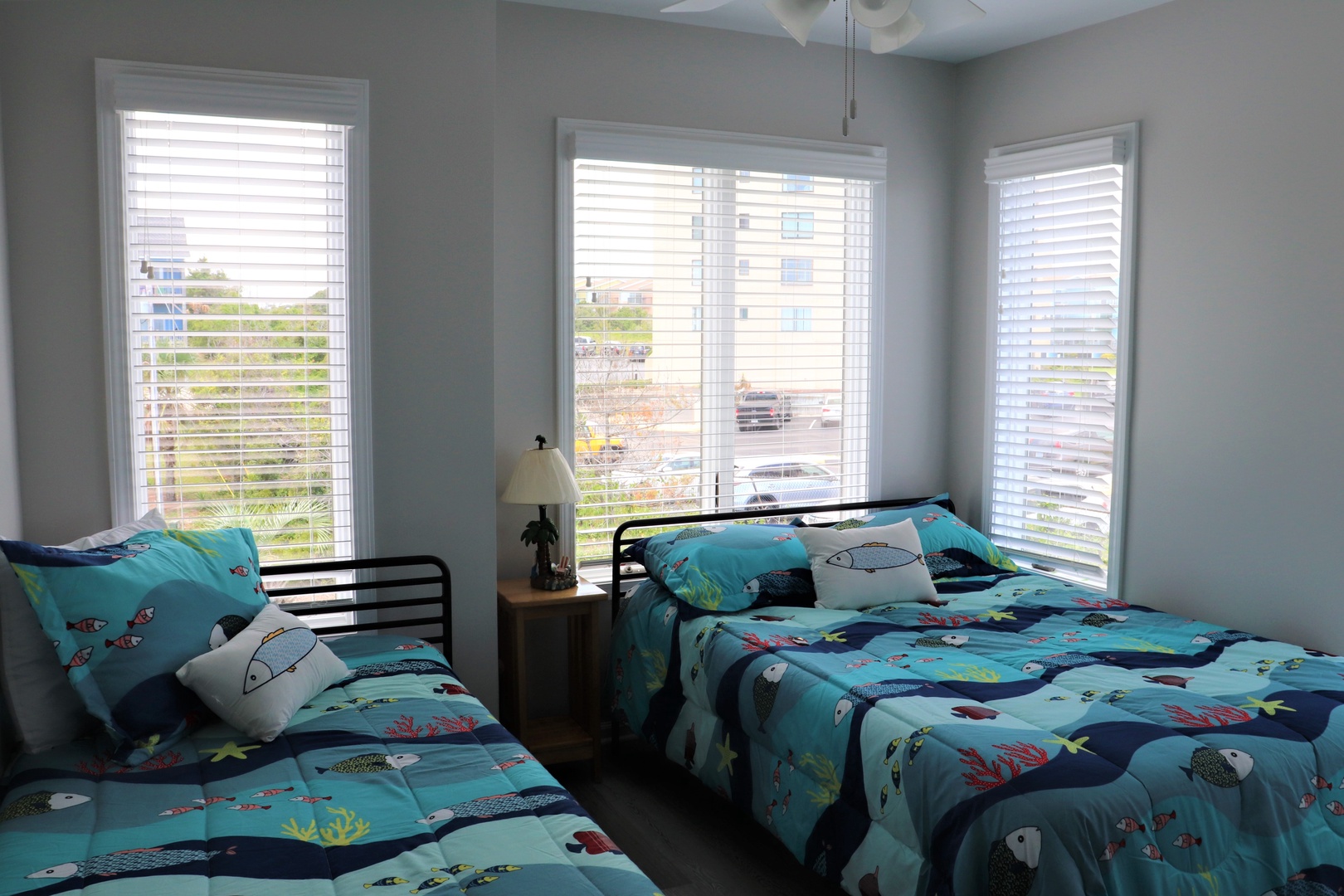 Rest in this cheerful twin bedroom where ocean-themed bedding and abundant natural light create a playful, comfortable retreat for your family vacation.