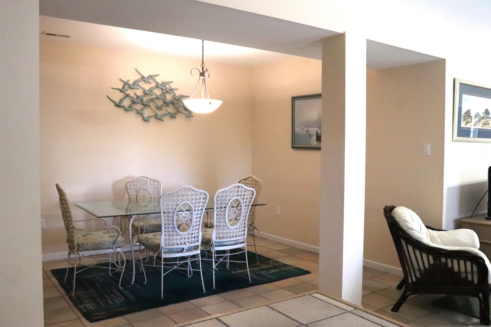 Your elegant dining area features a glass table with charming white chairs under soft pendant lighting, perfect for memorable meals together.