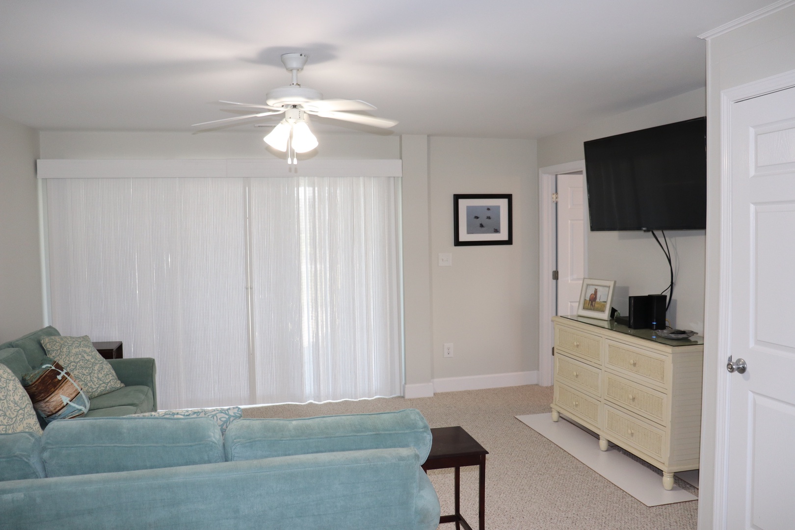 Unwind in your spacious living room with comfortable seating, ceiling fan, and entertainment center—perfect for relaxing after beach days.