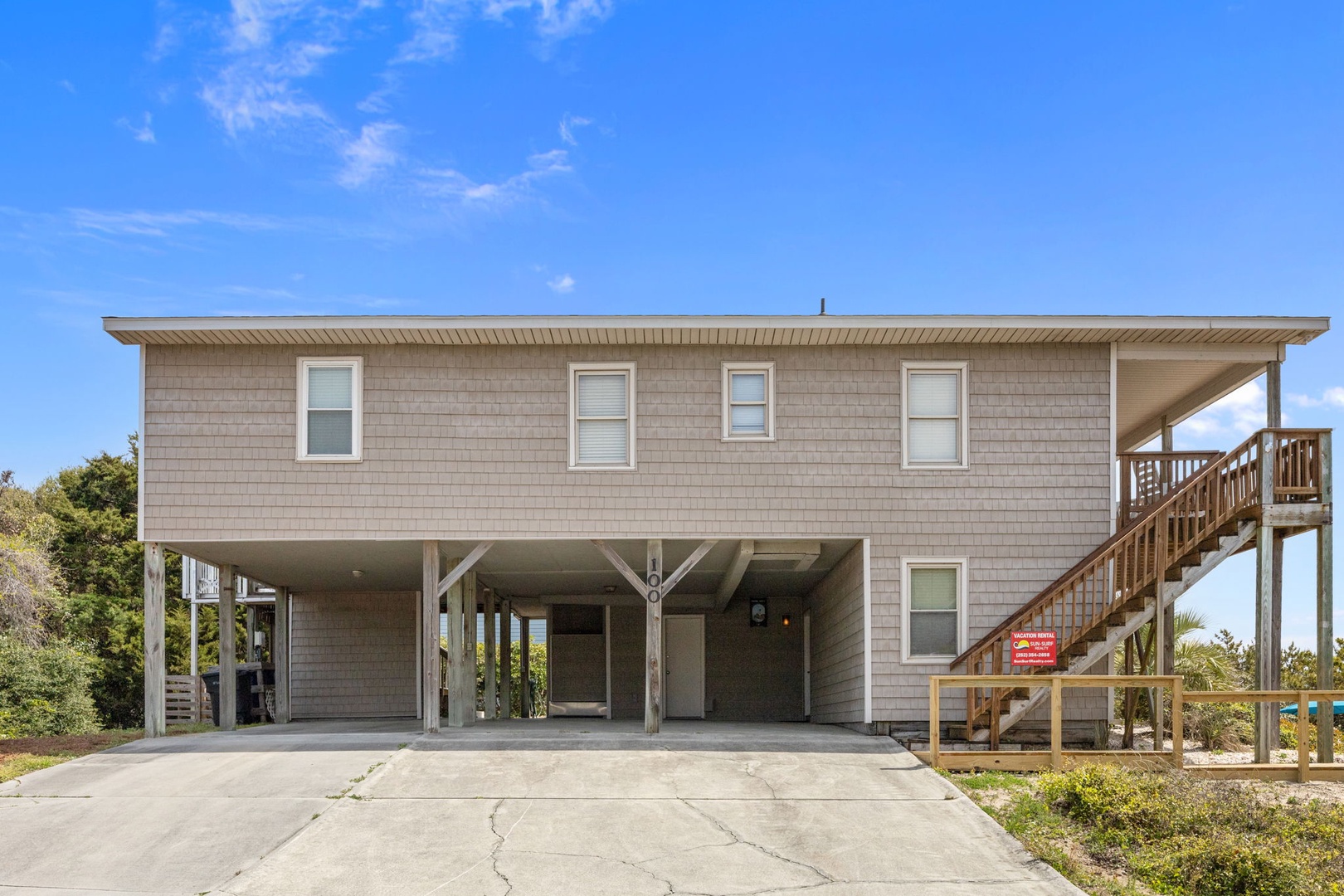 Coastal retreat with elevated design features covered parking and wooden deck stairs leading to your beachside getaway.