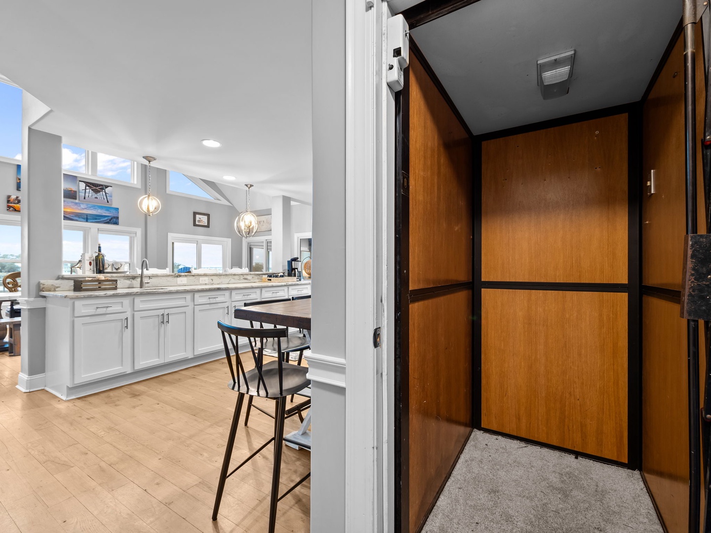 Step into your elegant elevator with warm wood paneling, providing easy access to your stylish kitchen with marble counters and modern fixtures.