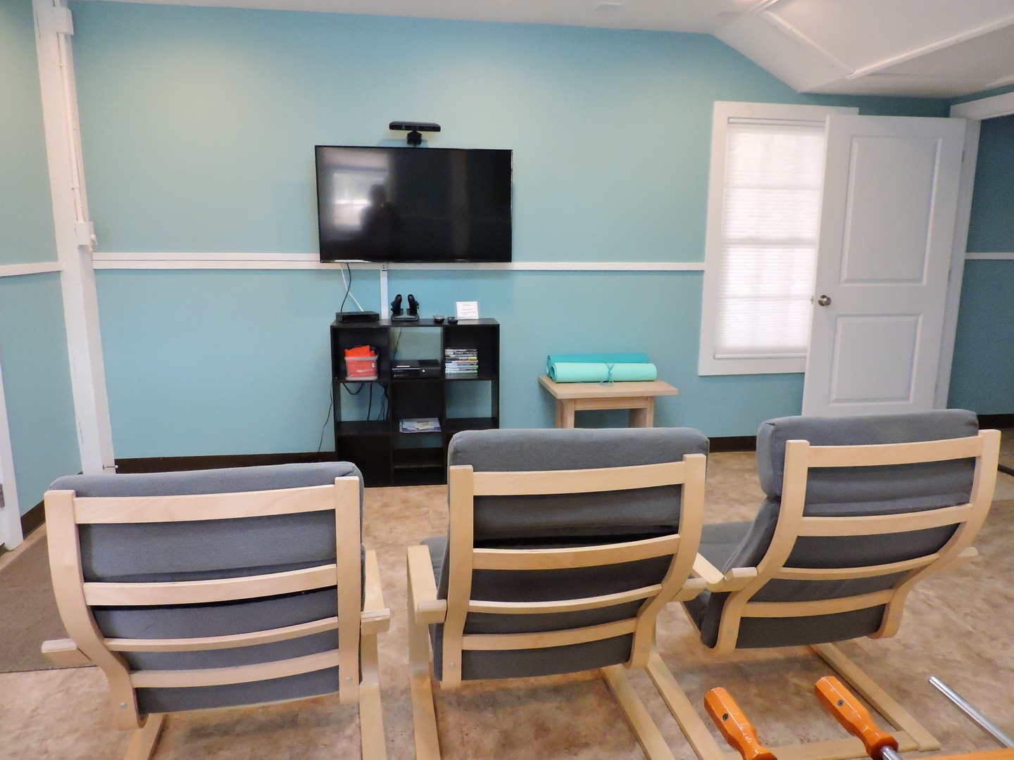 Settle into comfortable seating for your movie night in this relaxing communal space with calming blue walls and entertainment setup.