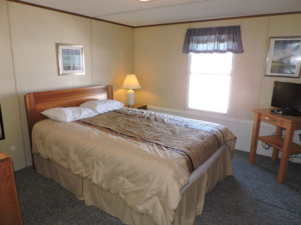 Settle into your comfortable queen bed with crisp linens and warm lighting from the bedside lamp for restful nights.