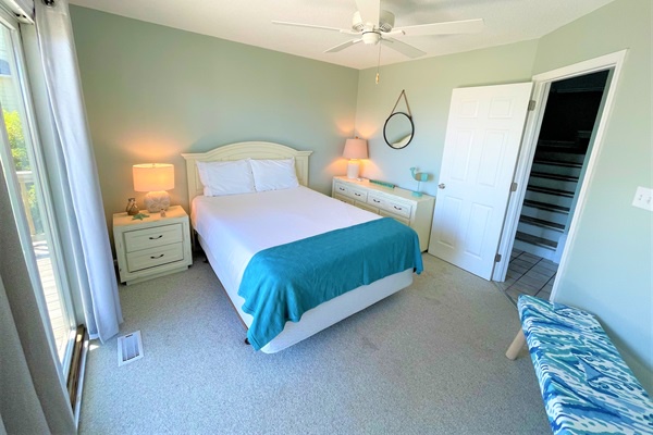 Relax in your serene coastal bedroom with crisp white linens, turquoise accents, and gentle sea breezes through the sliding doors.