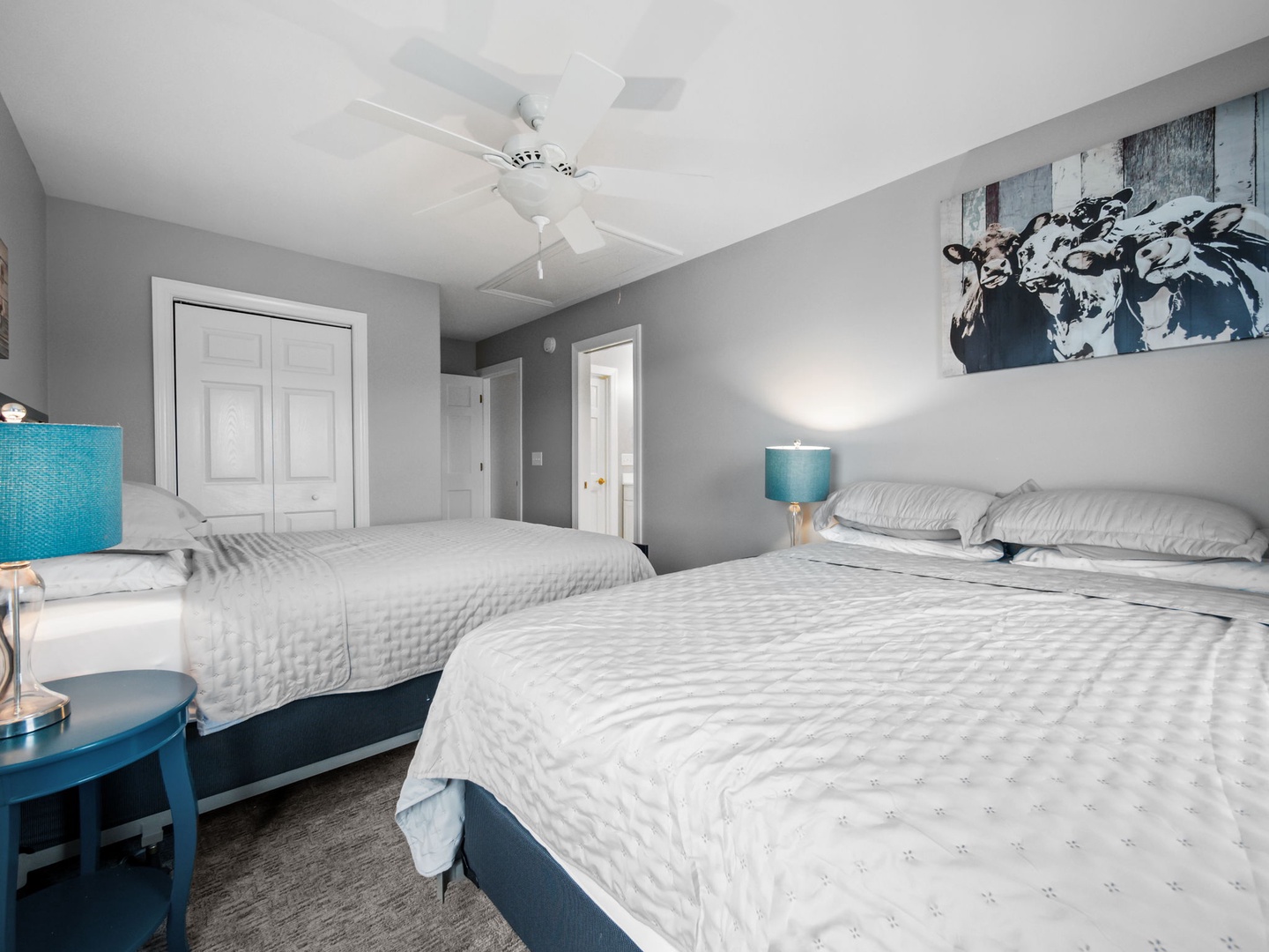 Rest comfortably in your dual-bed room featuring crisp linens, modern artwork, and soothing gray tones with pops of turquoise color.