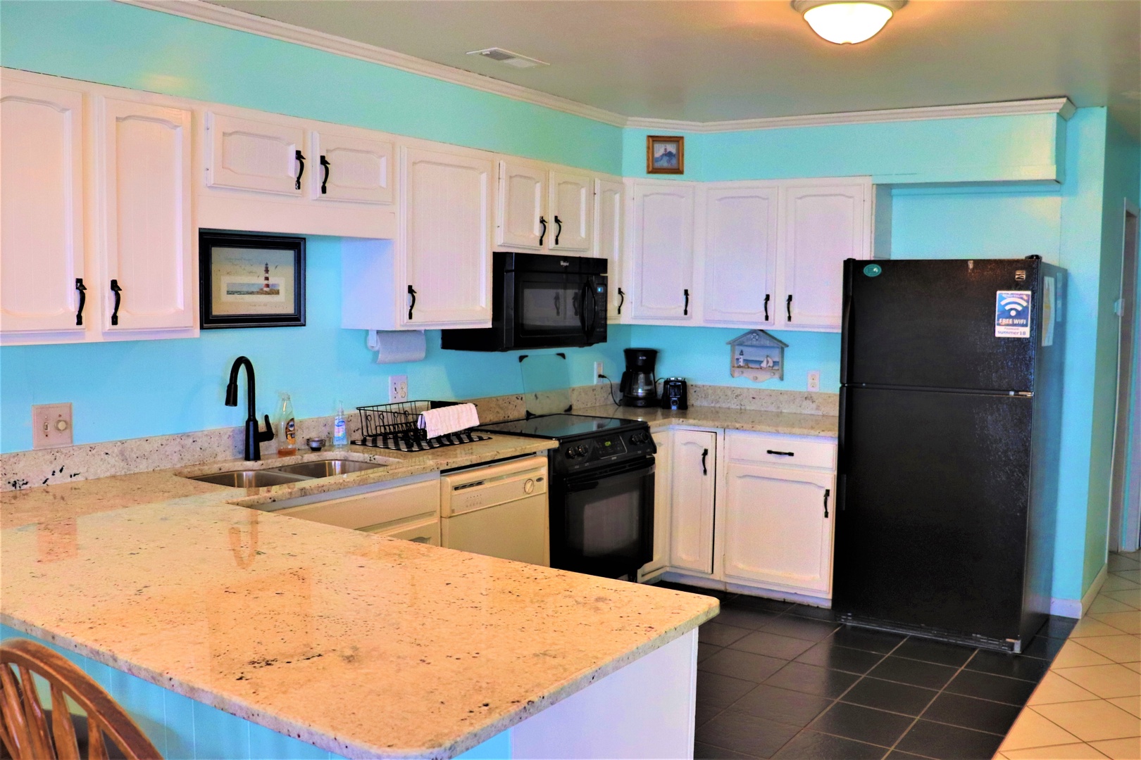 Your fully equipped kitchen awaits with granite counters, modern appliances, and vibrant coastal charm for memorable meal preparations.