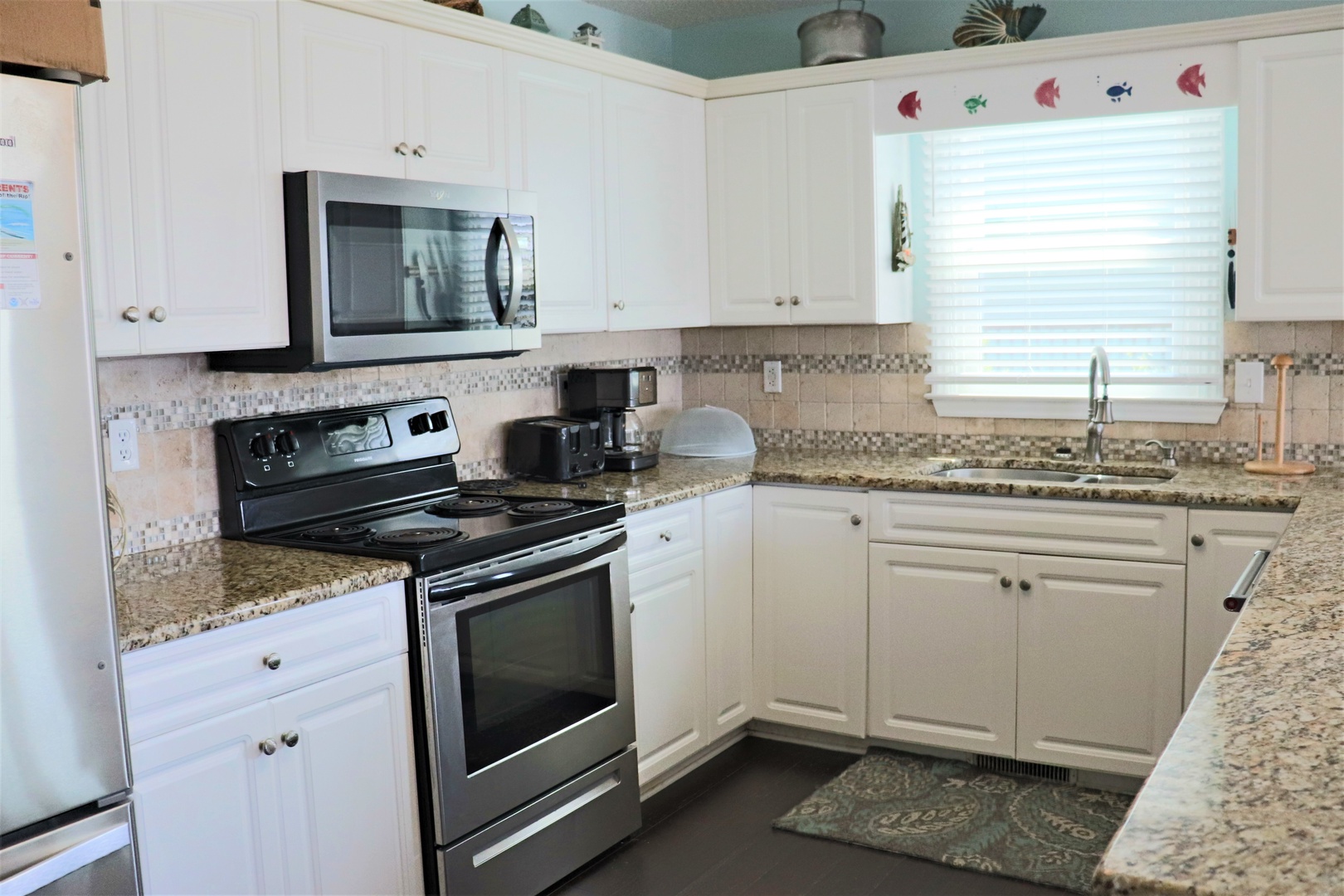 Your fully equipped kitchen awaits with granite countertops, modern appliances, and cheerful coastal touches—perfect for preparing memorable meals during your stay.