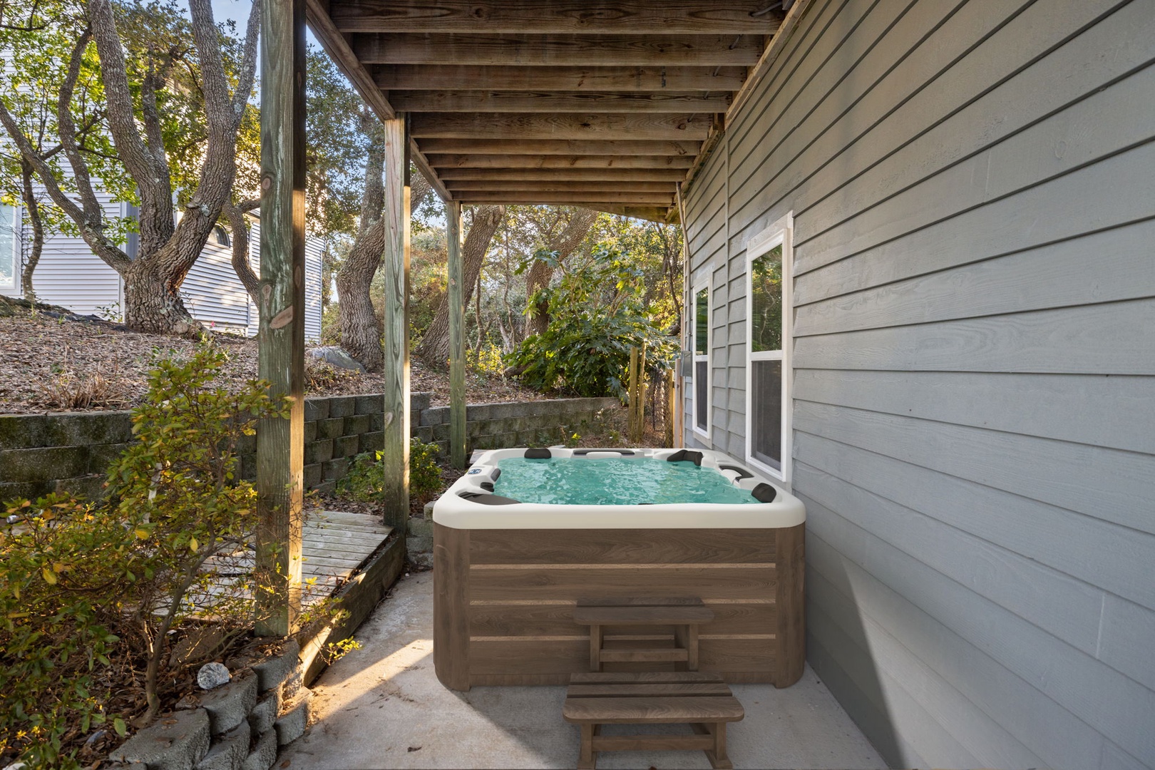 Slip into your private hot tub beneath the covered patio, where warm bubbles and tree-lined tranquility create the perfect evening retreat.