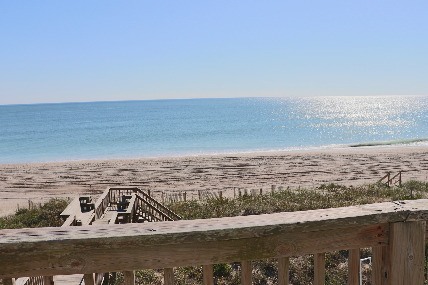 Pristine beach access with wooden boardwalk leading directly to sandy shores and crystal-clear waters.