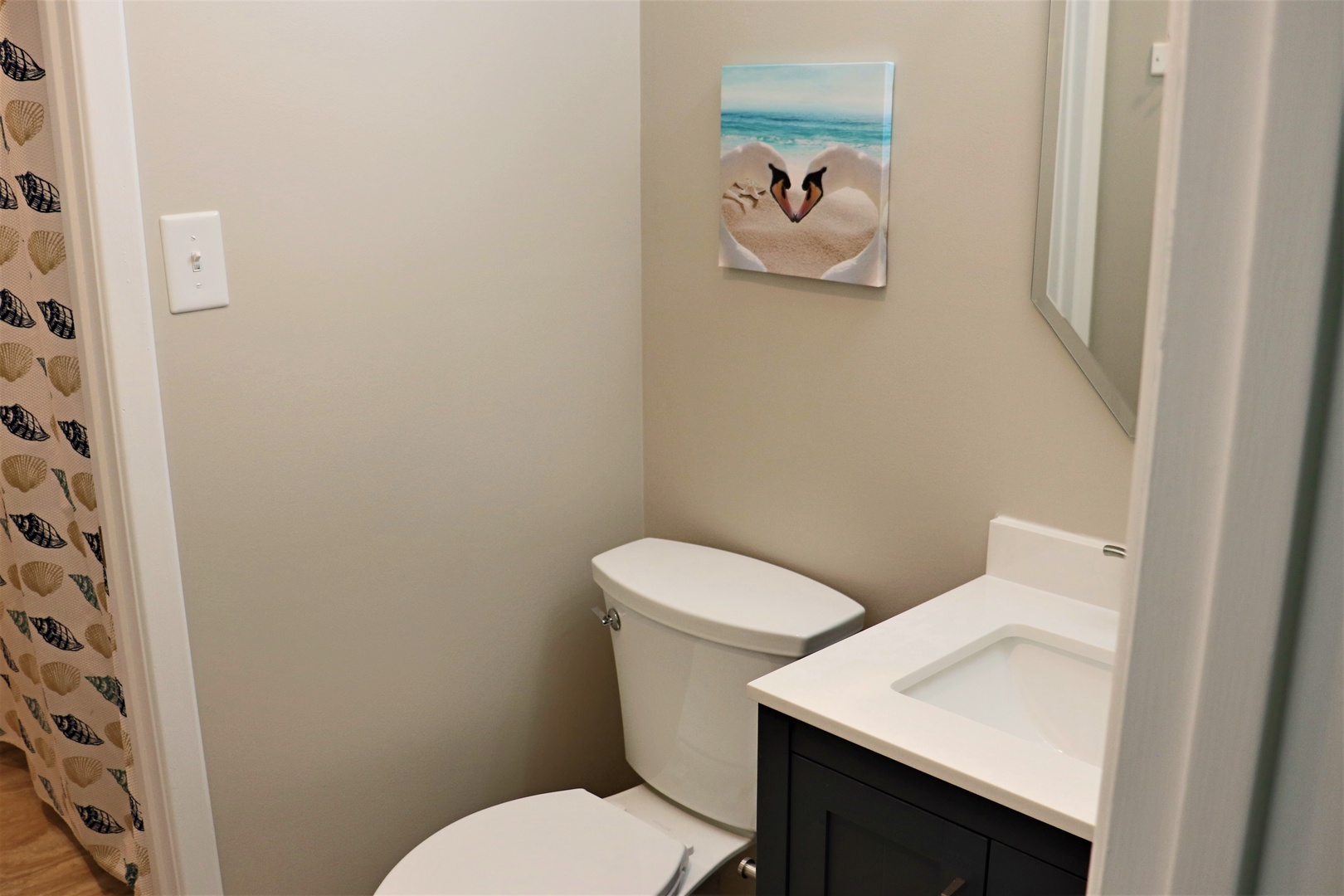 Your private bathroom features modern fixtures and coastal artwork, creating a serene space to refresh during your stay.