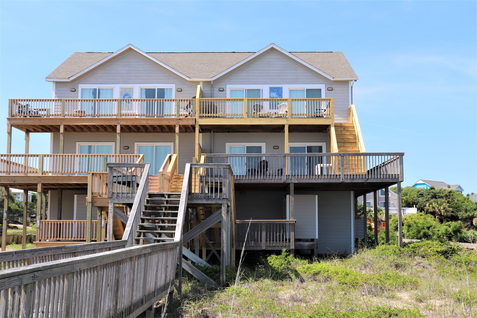 Multi-level beachfront property with expansive decks and direct beach access via wooden walkways.