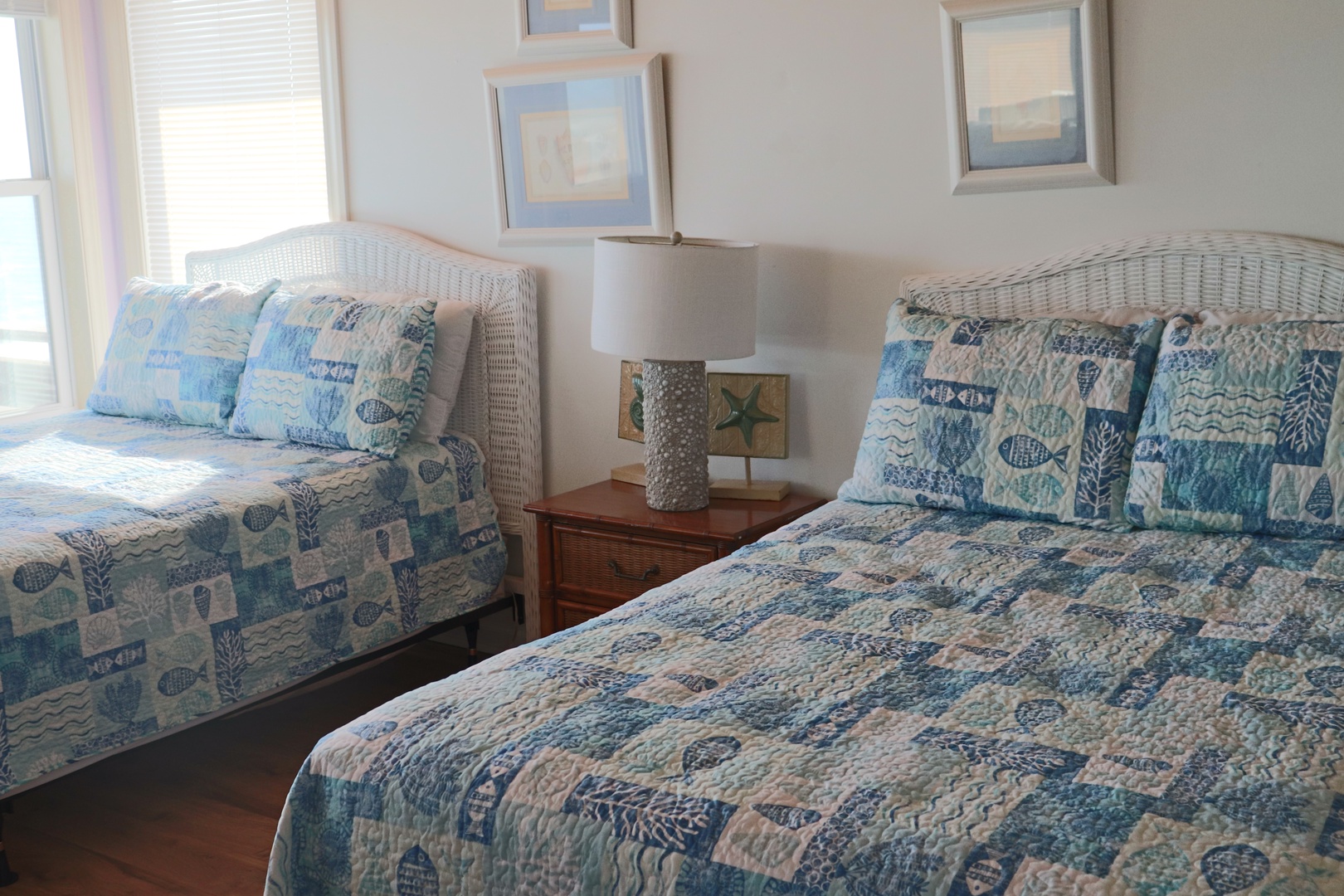 Your coastal-themed twin bedroom features crisp blue quilts and wicker headboards, perfect for sharing peaceful mornings with ocean-inspired comfort.