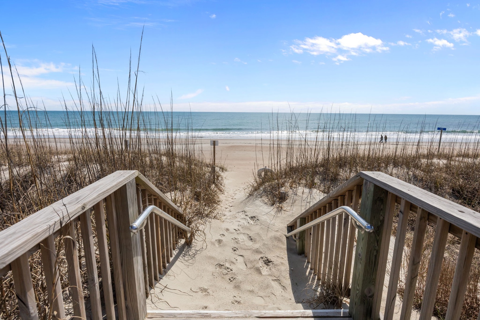 Pristine beach access with wooden boardwalk leading to sandy shores and ocean waves.