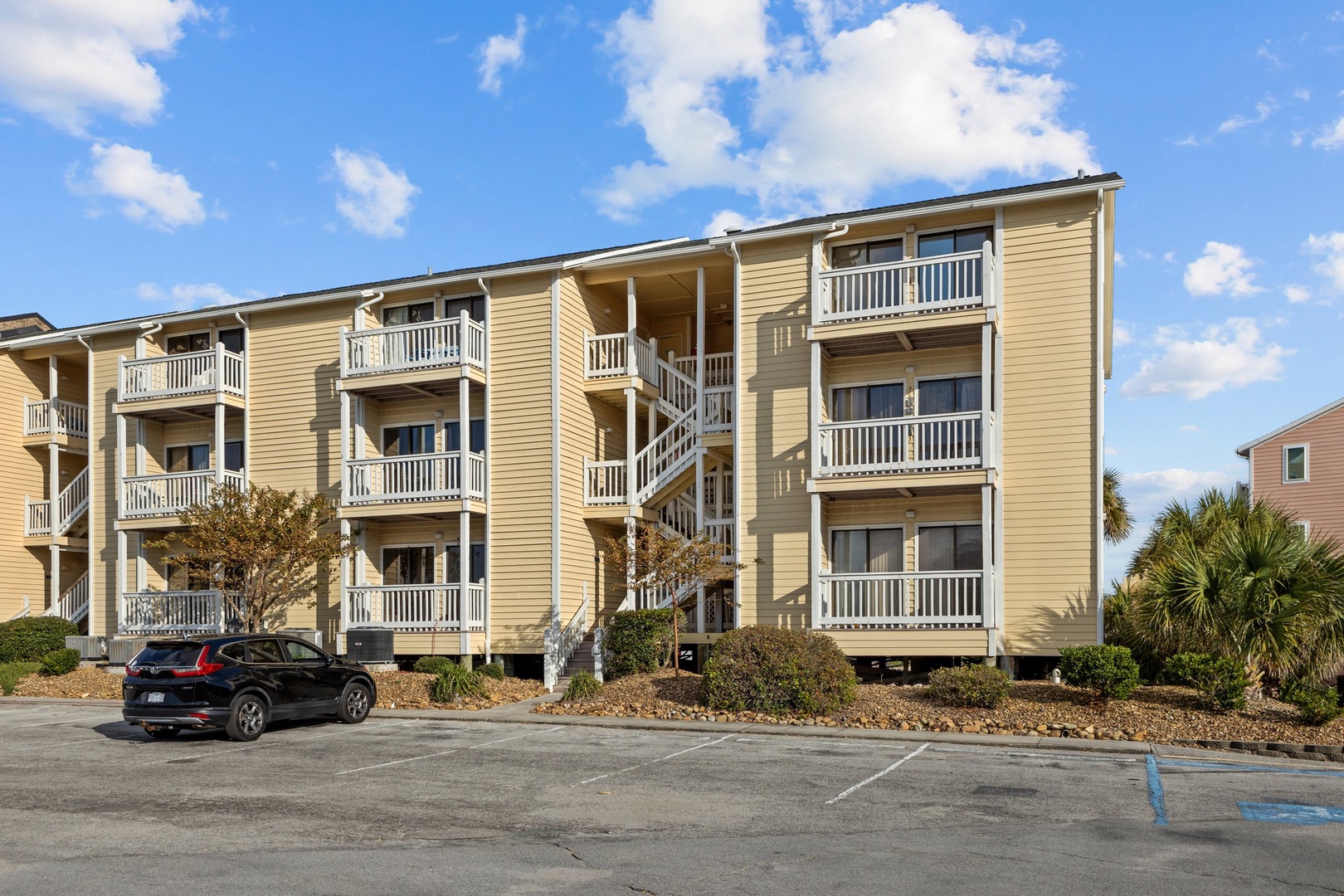 Multi-story beachside property building featuring comfortable balconies and convenient parking in a peaceful coastal setting.