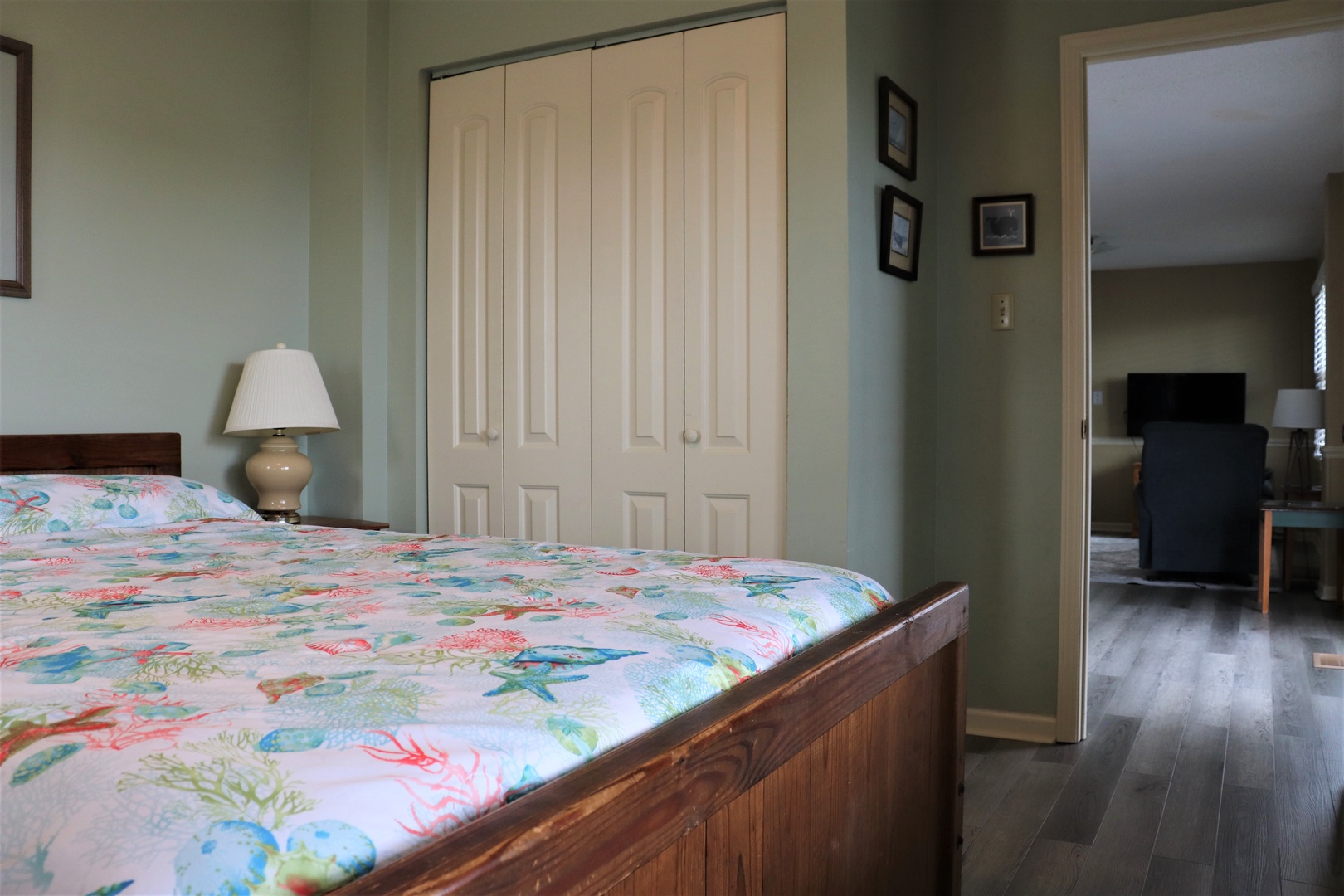 Your comfortable bedroom features a cozy wooden bed with tropical linens, ample closet space, and flows into your bright living area.