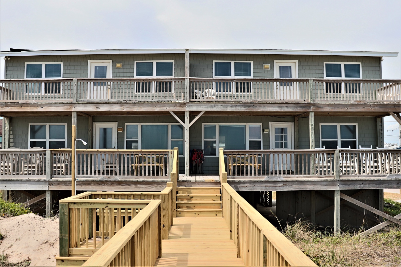 Beachfront property with multiple units, elevated on stilts with wooden walkways leading to private balconies overlooking the shore.