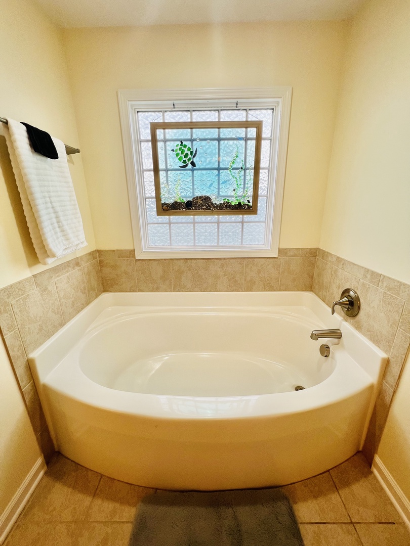 Sink into this deep soaking tub while watching greenery through your private garden window—pure relaxation awaits.