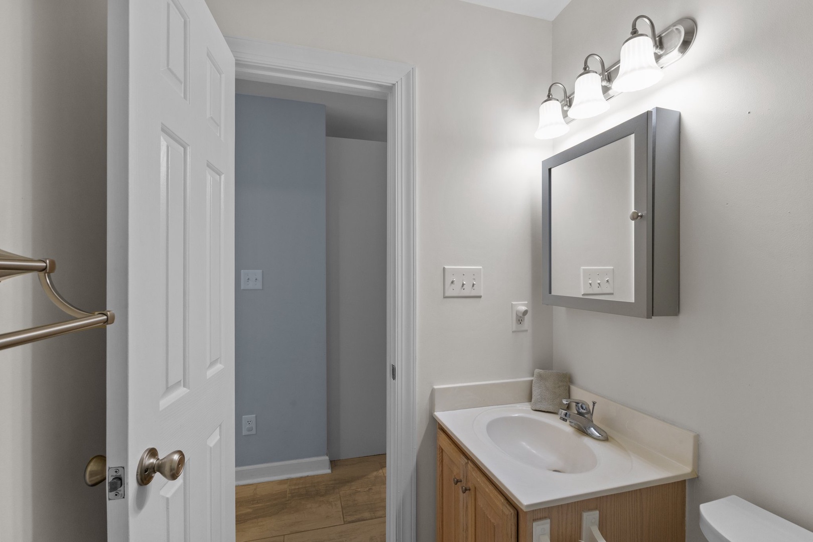 Your bright, well-lit bathroom features modern vanity lighting and warm wood cabinetry for a comfortable morning routine.
