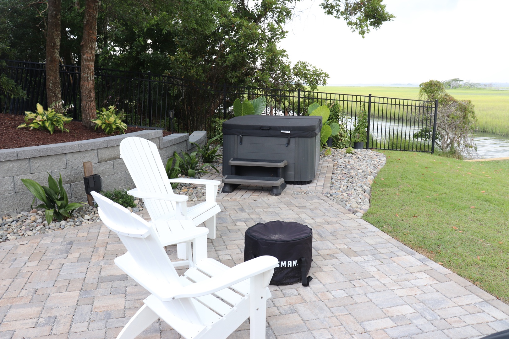 Unwind in your private outdoor oasis with cozy seating, a relaxing hot tub, and peaceful views of lush green fields.