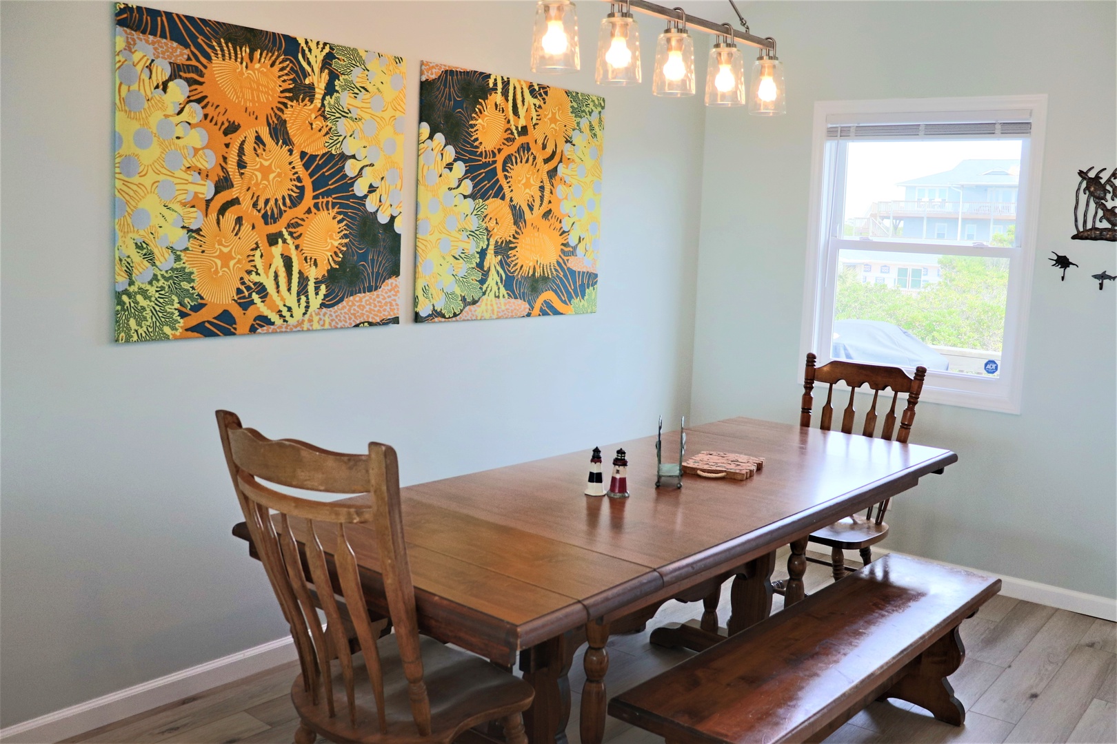 Your dining space features warm wood tones, vibrant tropical artwork, and pendant lighting for memorable meals together.