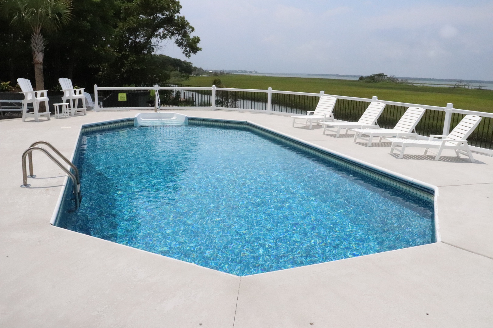 Sparkling pool deck with comfortable loungers where you'll soak up sun while enjoying peaceful marsh views.