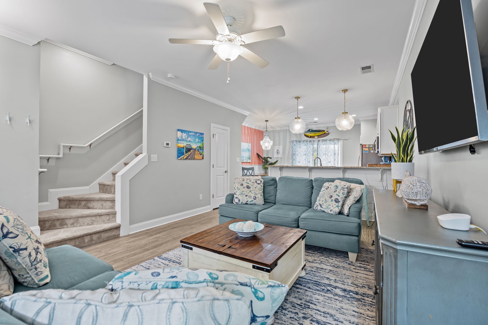 Relax in your bright, coastal-themed living space with comfortable seating, modern kitchen, and airy open layout perfect for unwinding.