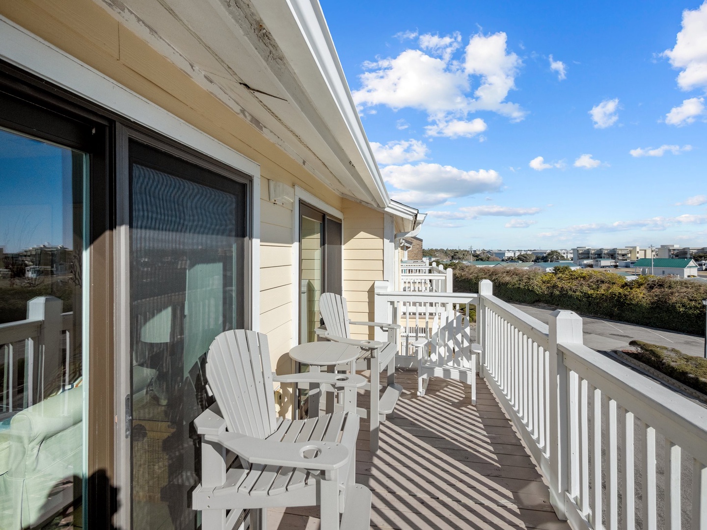 Step onto your private balcony where comfortable chairs await your morning coffee, offering peaceful neighborhood views under bright blue skies.