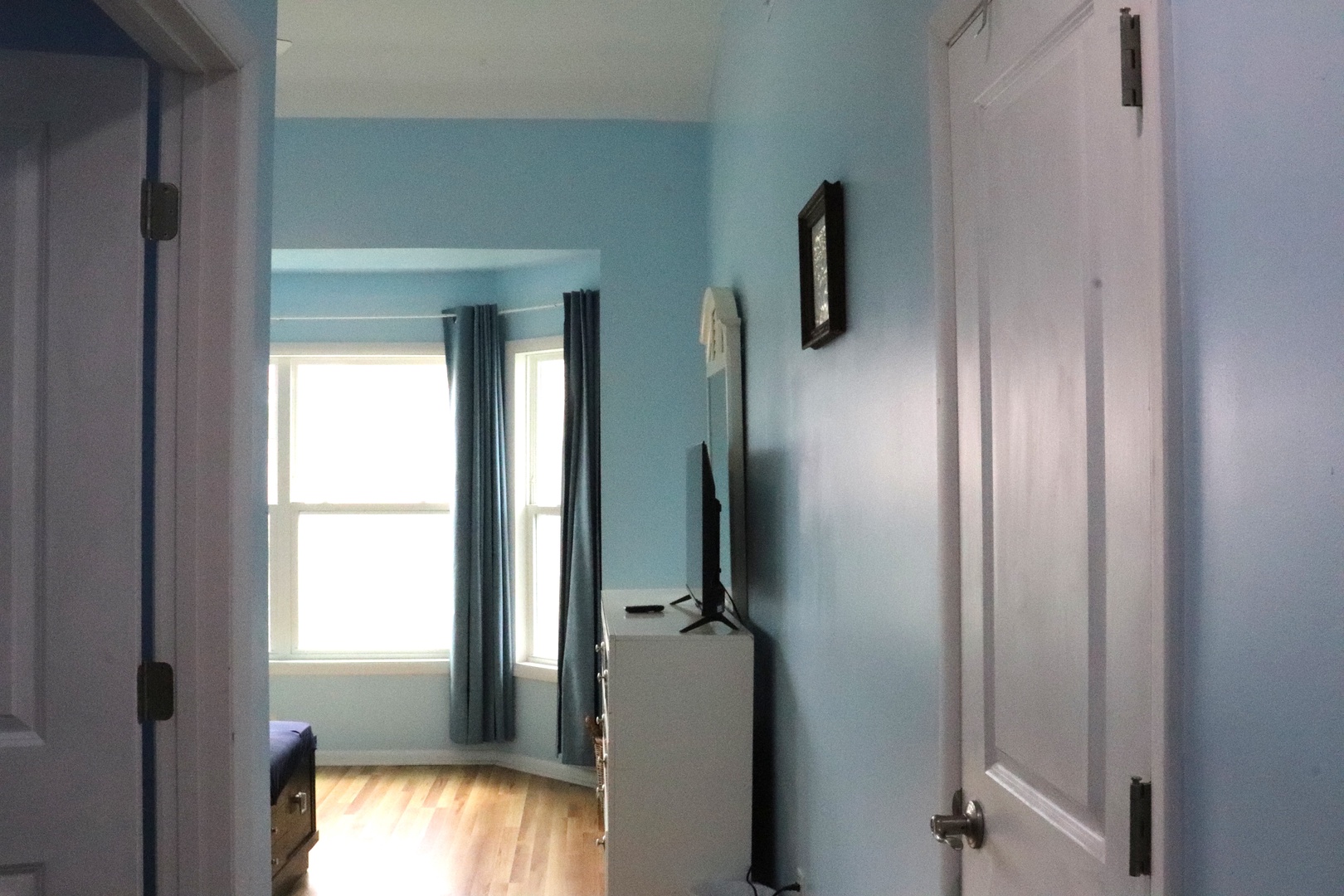 Step into your peaceful private hallway with soothing blue walls, natural light, and convenient access to your bedroom—your calm retreat awaits just beyond.