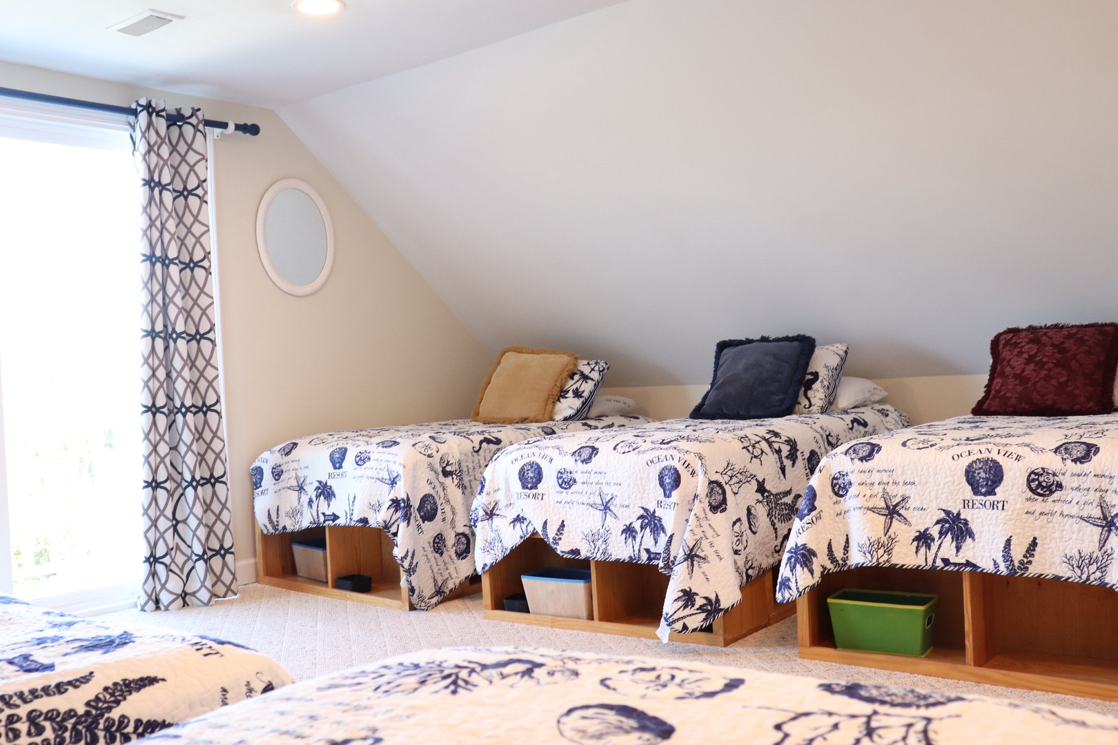 Unwind in your cozy retreat with twin beds featuring tropical-themed linens and thoughtful storage compartments beneath.