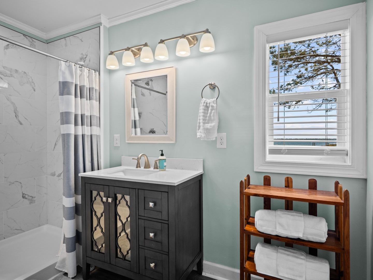 Refresh in your spa-like bathroom with soothing mint walls, marble shower, and waterside views through the window.