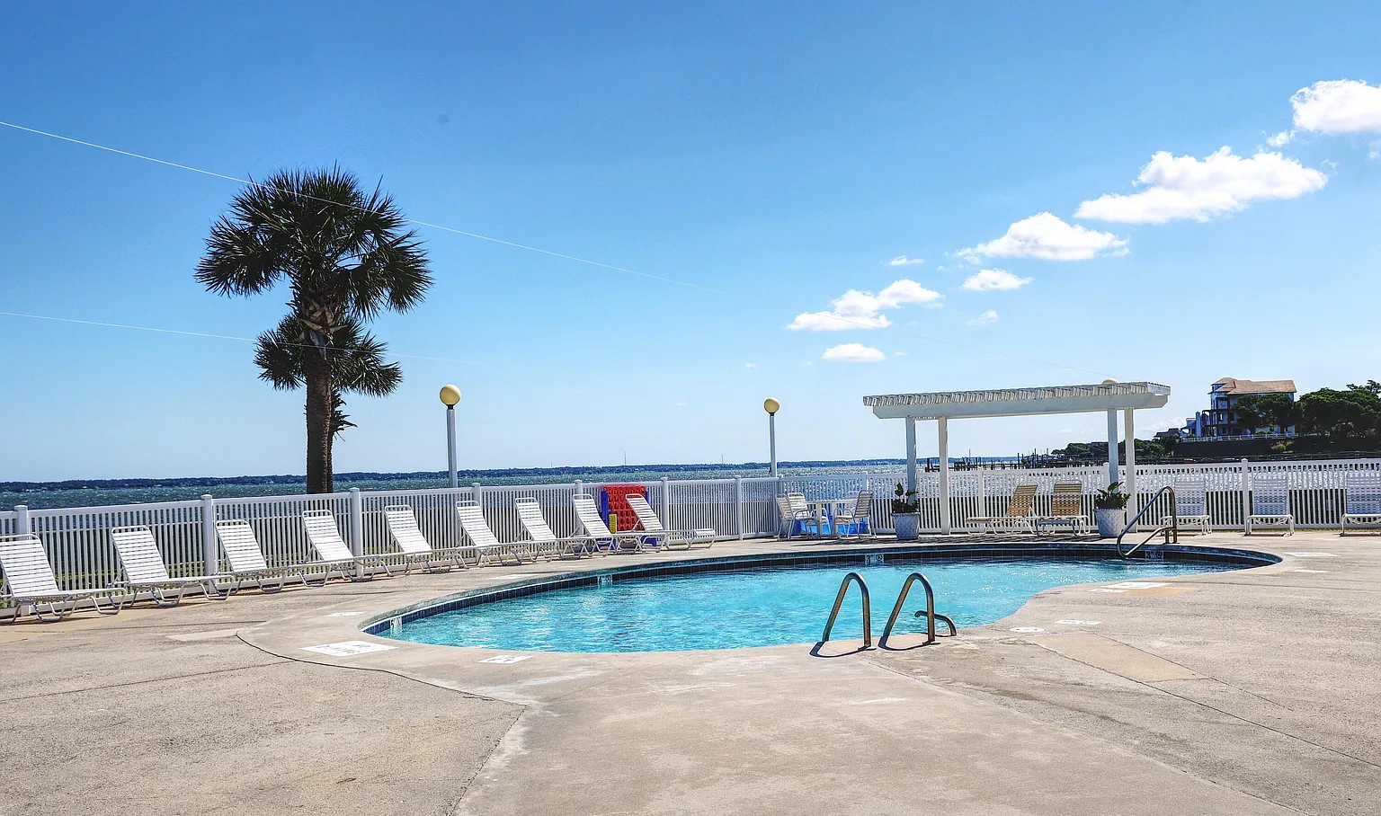 Beachfront pool deck featuring crystal-clear swimming pool with ocean views and lounge chairs for ultimate relaxation.