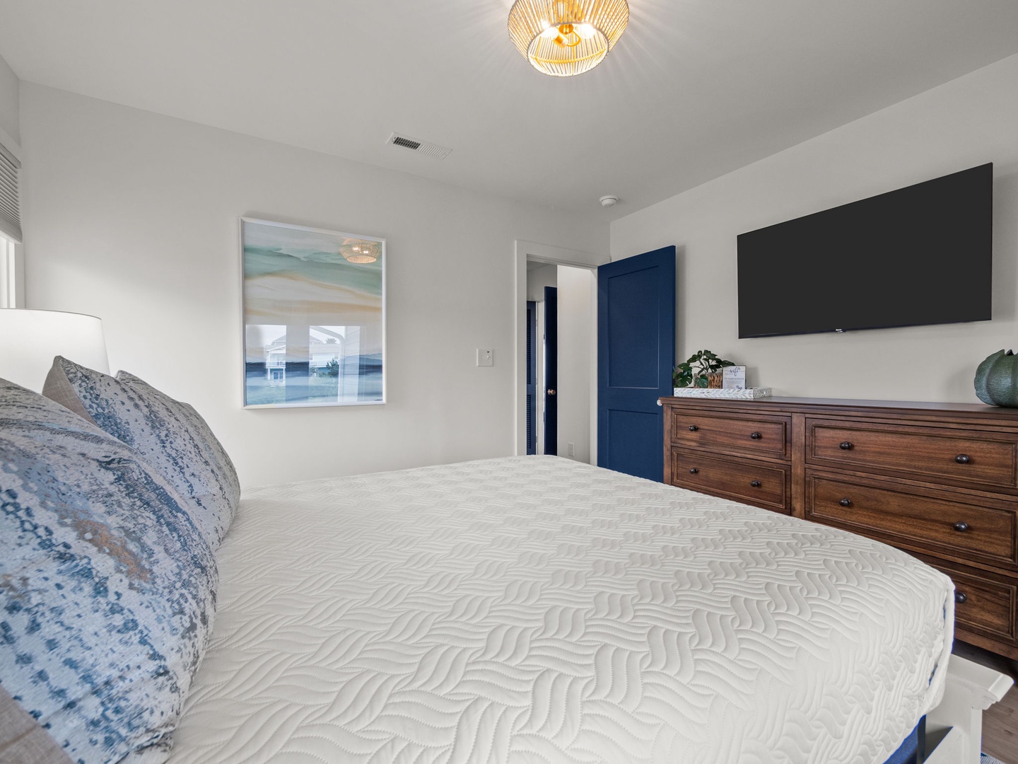 Rest easy in your peaceful bedroom featuring a plush mattress, warm wood furnishings, and modern coastal touches.