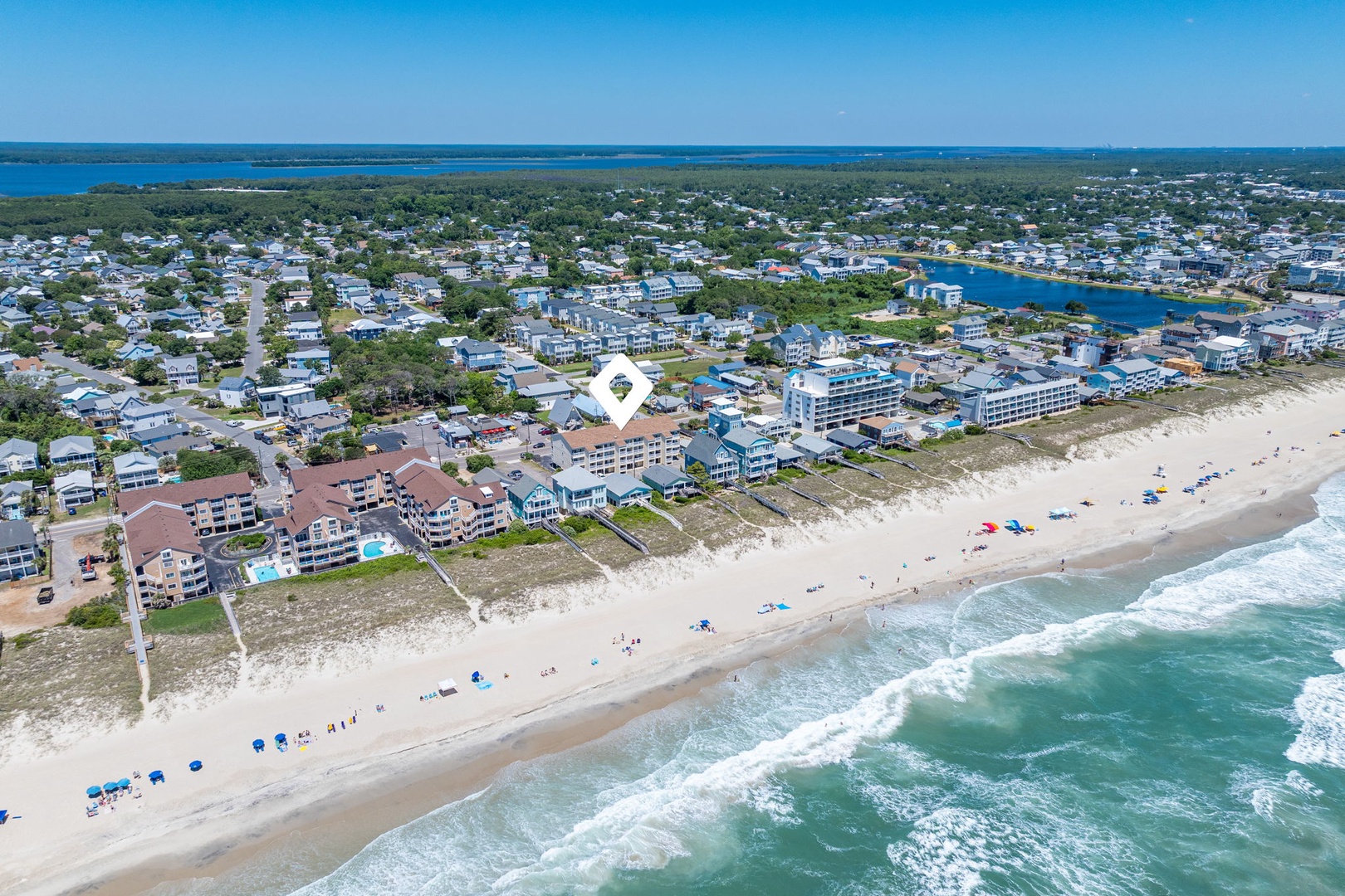 Aerial view of a beachfront vacation community with sandy shores, coastal properties, and waterways extending inland along the horizon.