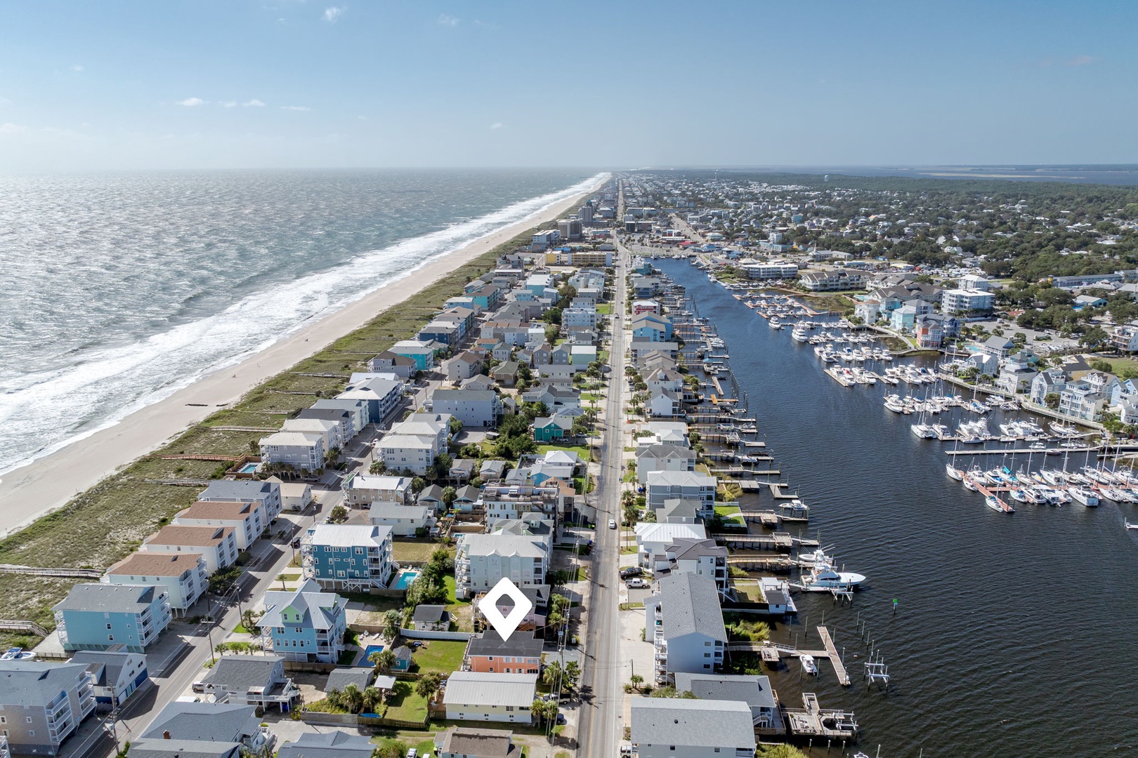Aerial view of a charming coastal community with pristine beaches, marina access, and waterfront homes nestled between ocean and harbor.