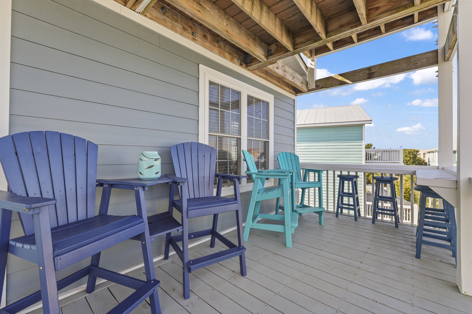 Step onto your private covered deck where cheerful Adirondack chairs and a high-top table await your morning coffee or sunset happy hour, all framed by coastal breezes and blue skies.