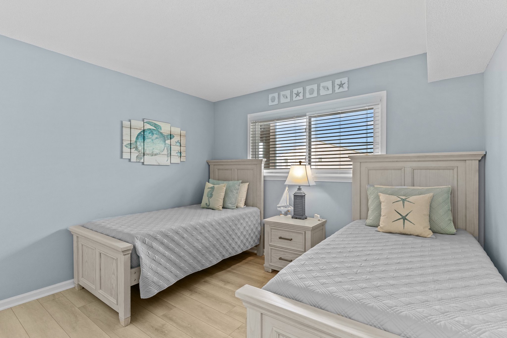 Two twin beds with coastal charm offer peaceful rest, while soft blue walls and ocean-themed decor create your perfect beachside retreat.