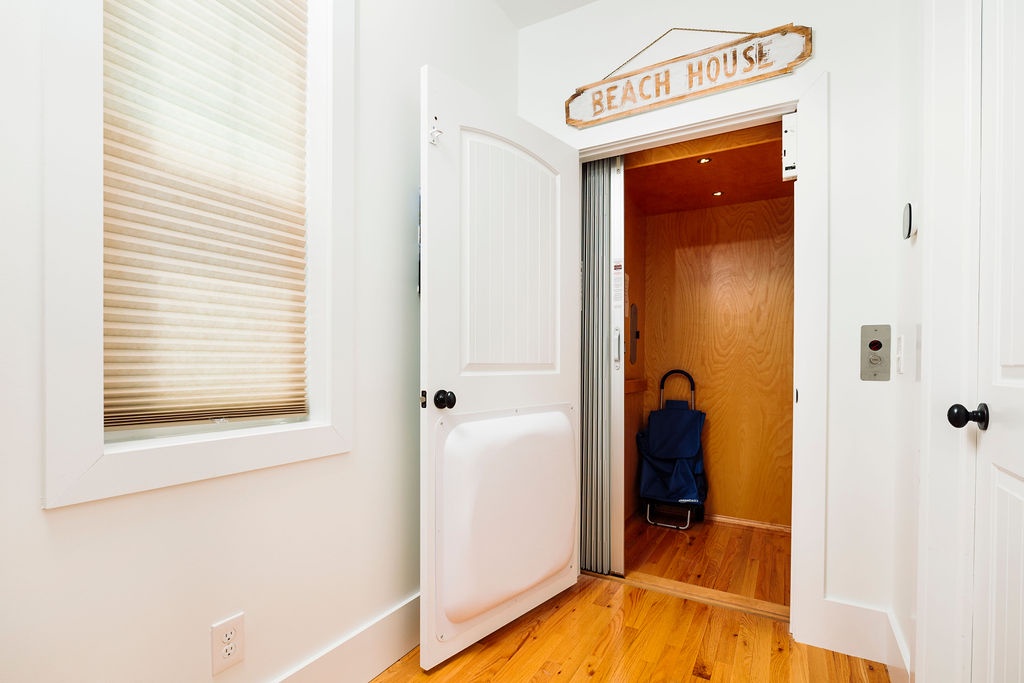 Step into your charming beach house retreat where warm wood floors and bright windows create a welcoming coastal atmosphere.